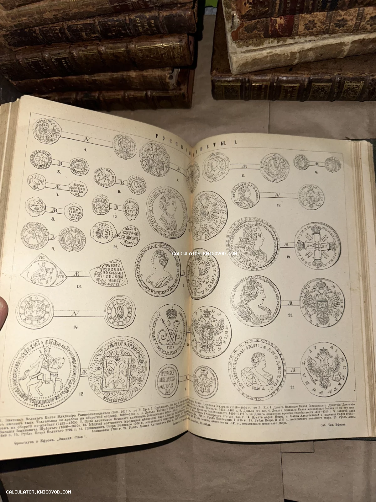 Разворот антикварной книги с литографией старинных русских монет на фоне стопки старых фолиантов.