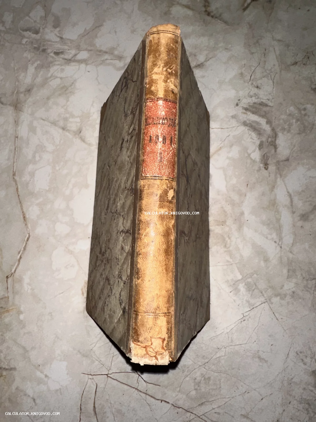 Вид на потертый корешок антикварной книги с мраморной бумагой на крышках переплета.