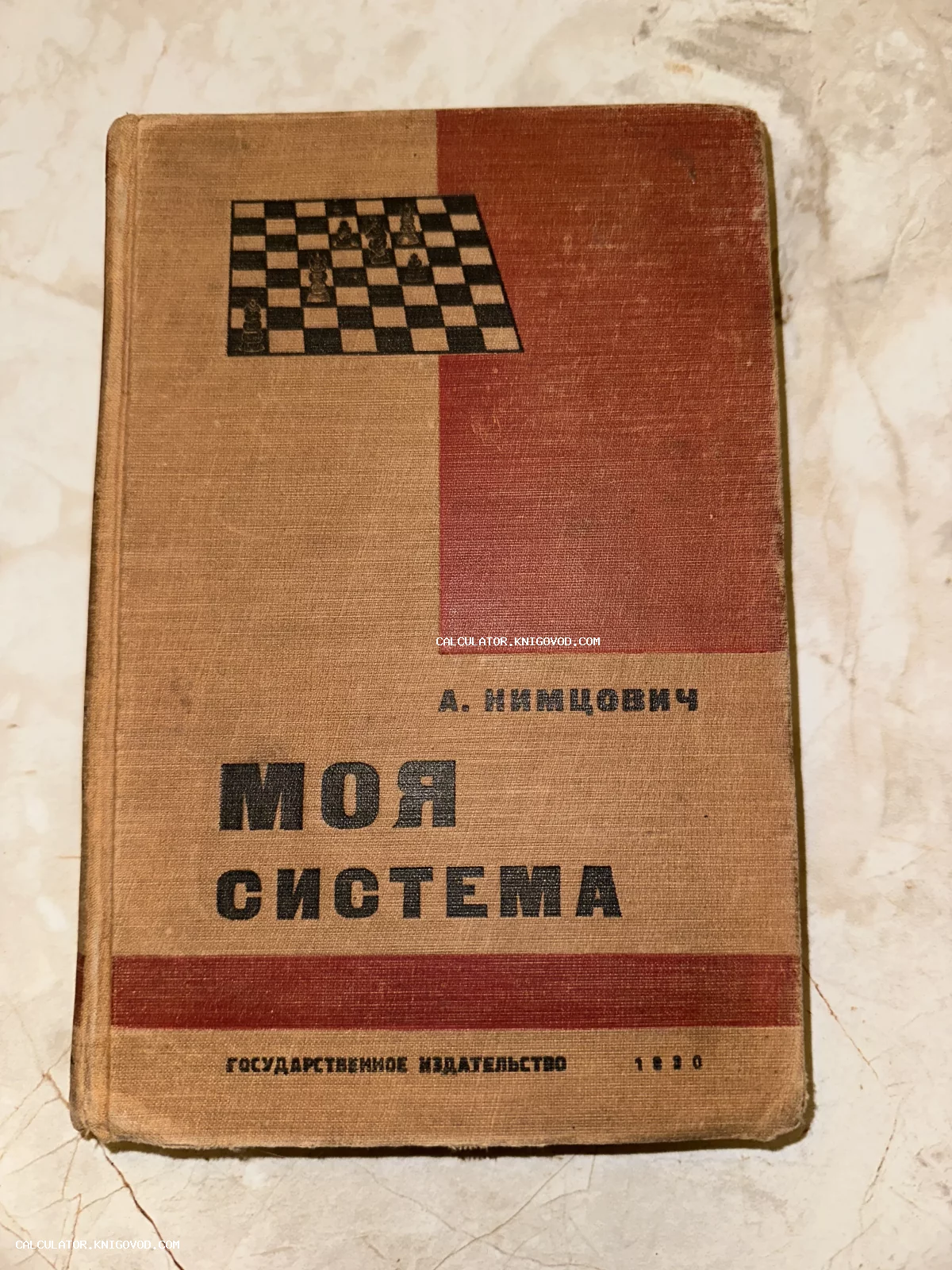 Старая книга Арона Нимцовича «Моя система» 1930 года издания в твердом переплете с шахматной доской на обложке.