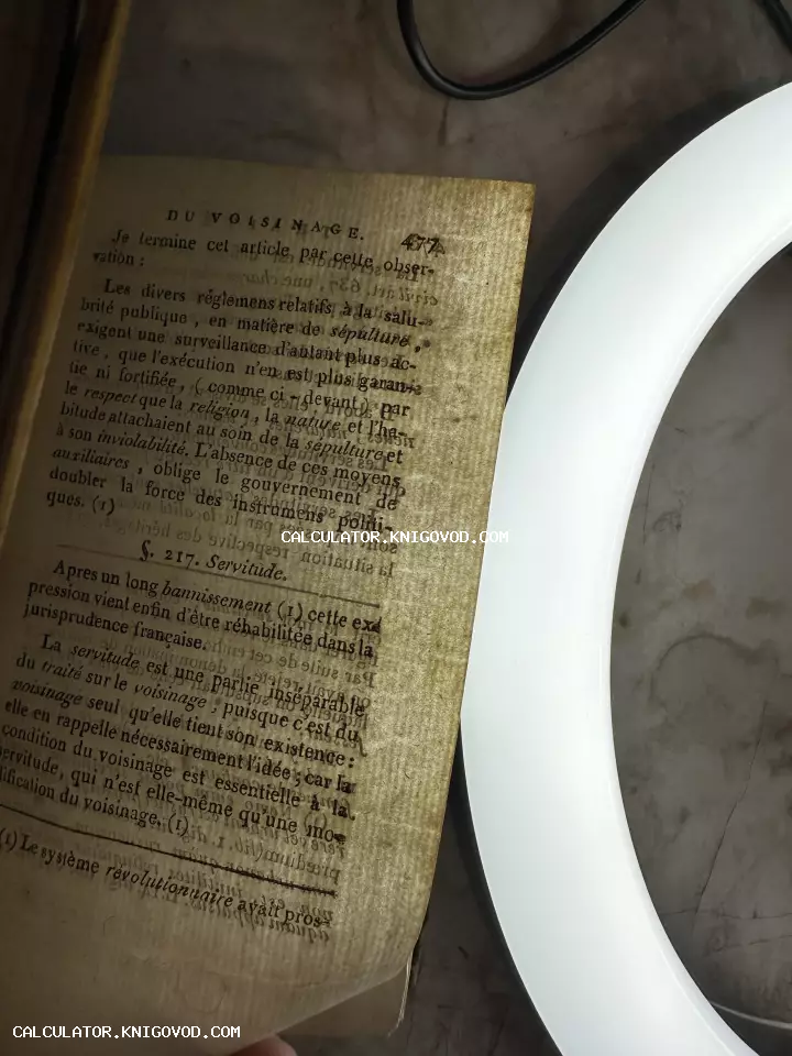 Пожелтевшая страница антикварной книги на французском языке с заголовком DU VOISINAGE под светом лампы.