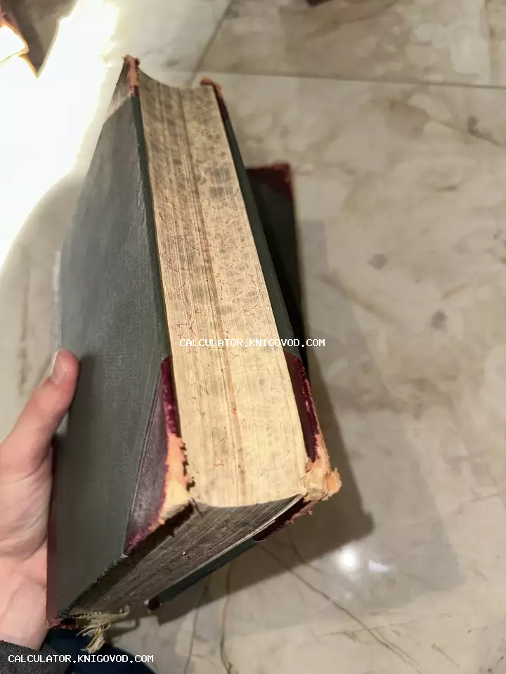 Вид на книжный блок старинной массивной книги с мраморным рисунком на срезе и потертыми углами переплета.