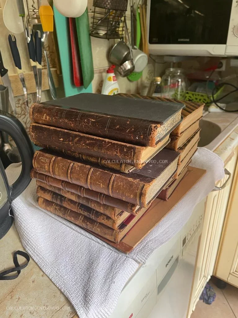 Стопка антикварных книг с потертыми кожаными корешками и золотым тиснением на белом полотенце.