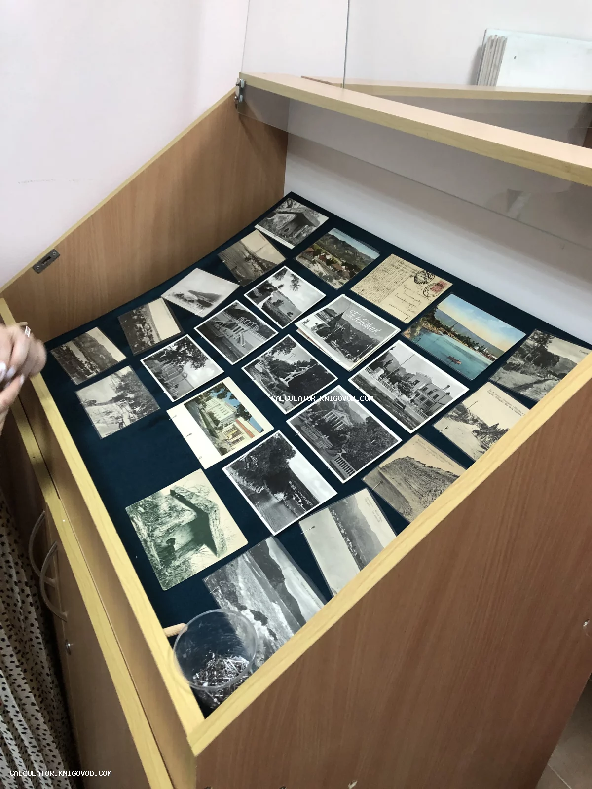 Деревянная витрина с разложенными старинными черно-белыми и цветными почтовыми открытками начала XX века.