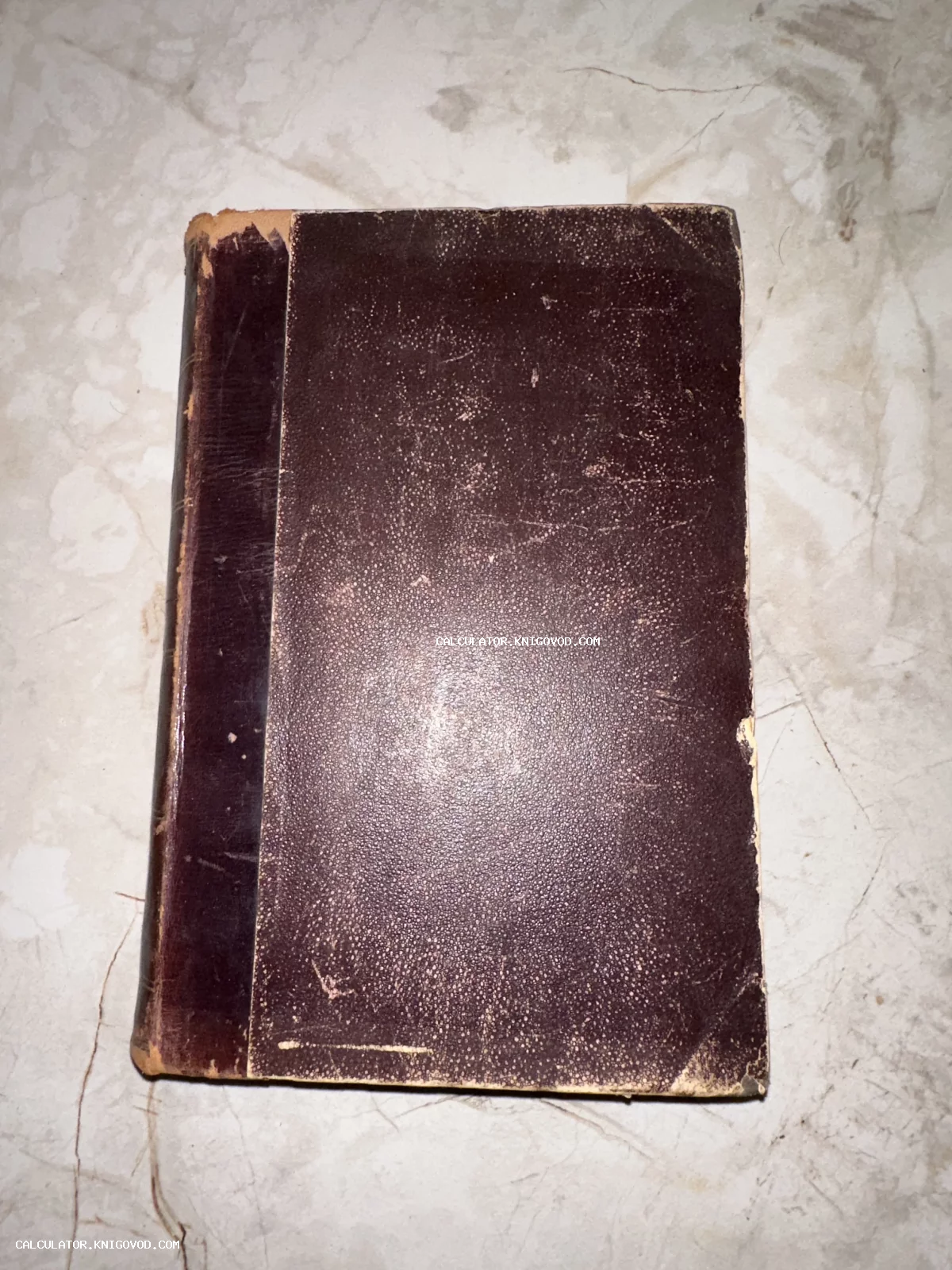 Старинная книга в темно-коричневом потертом кожаном переплете на светлой поверхности