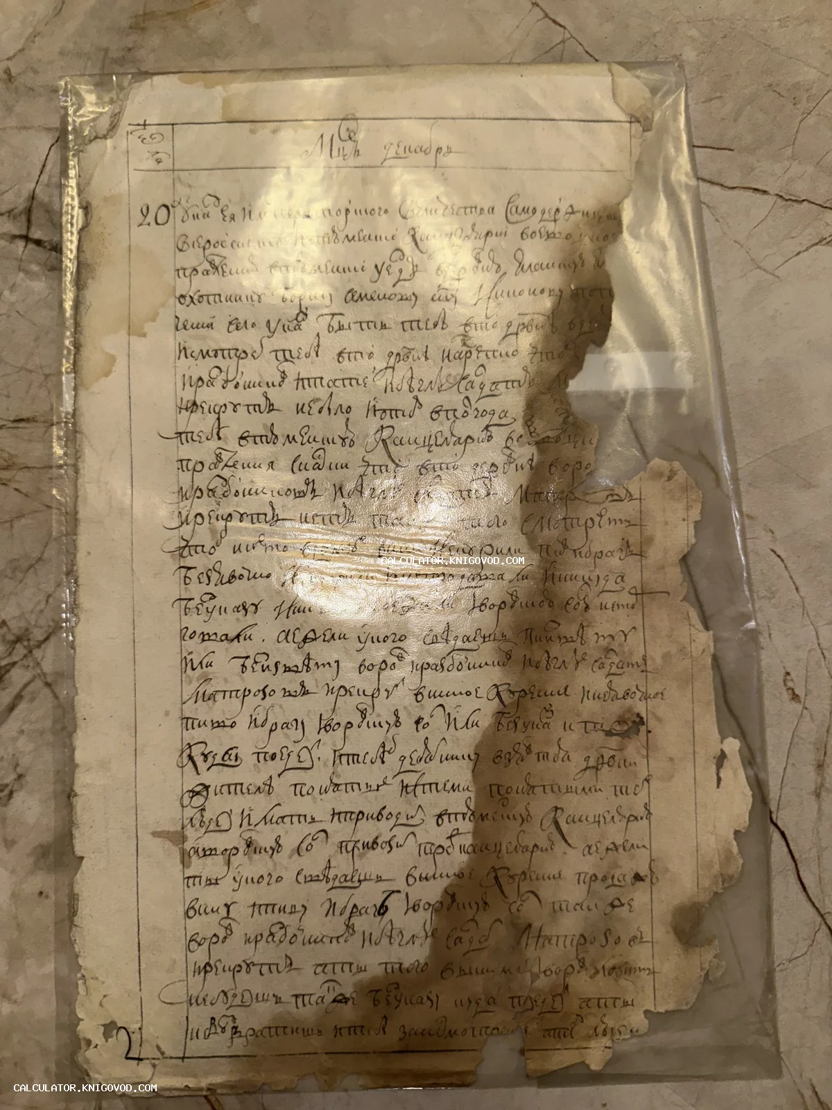 Старинный рукописный документ на пожелтевшей бумаге с оборванными краями в защитной пленке.