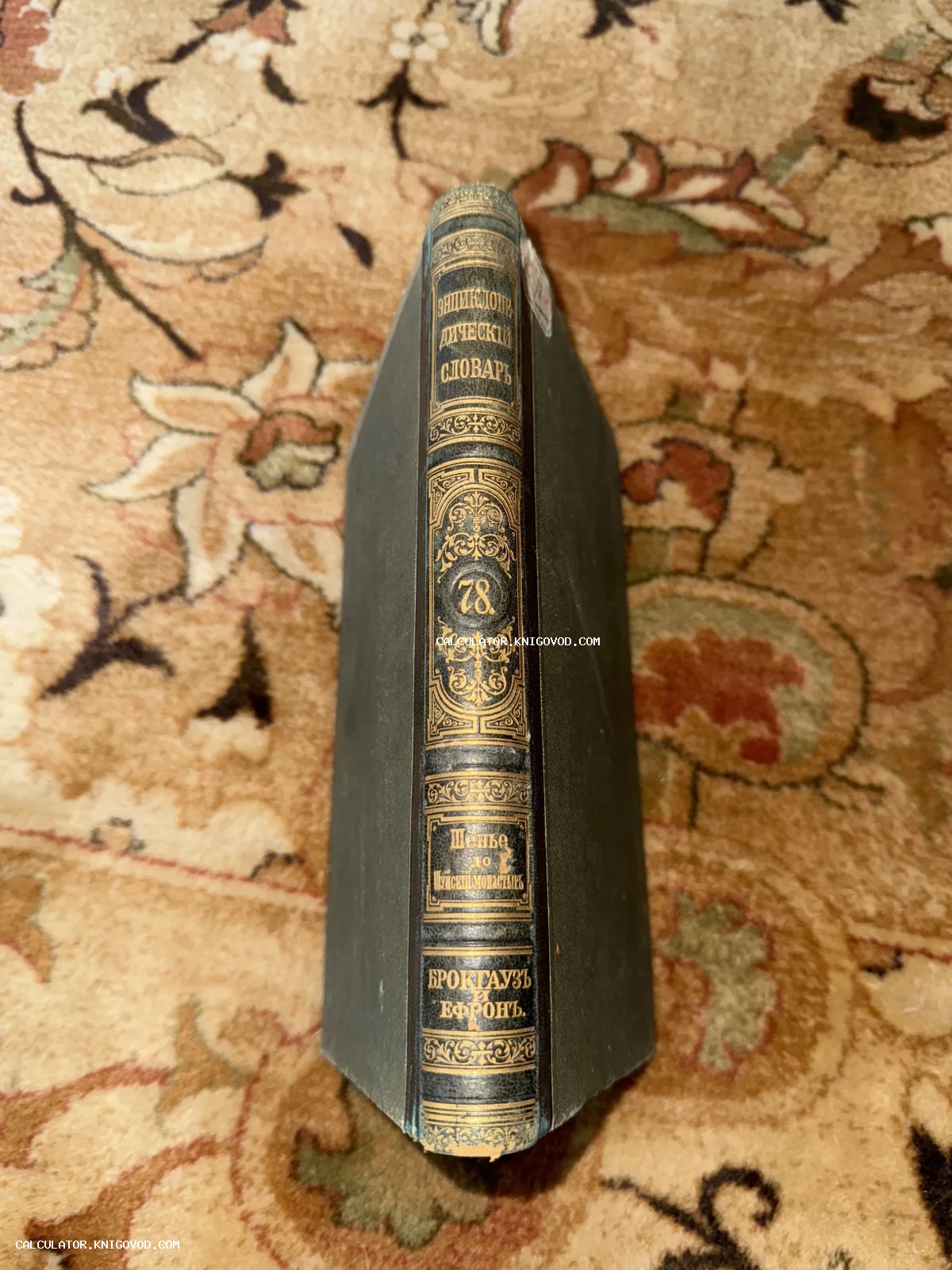 Корешок антикварной книги Энциклопедический словарь Брокгауза и Ефрона с золотым тиснением на узорчатом ковре