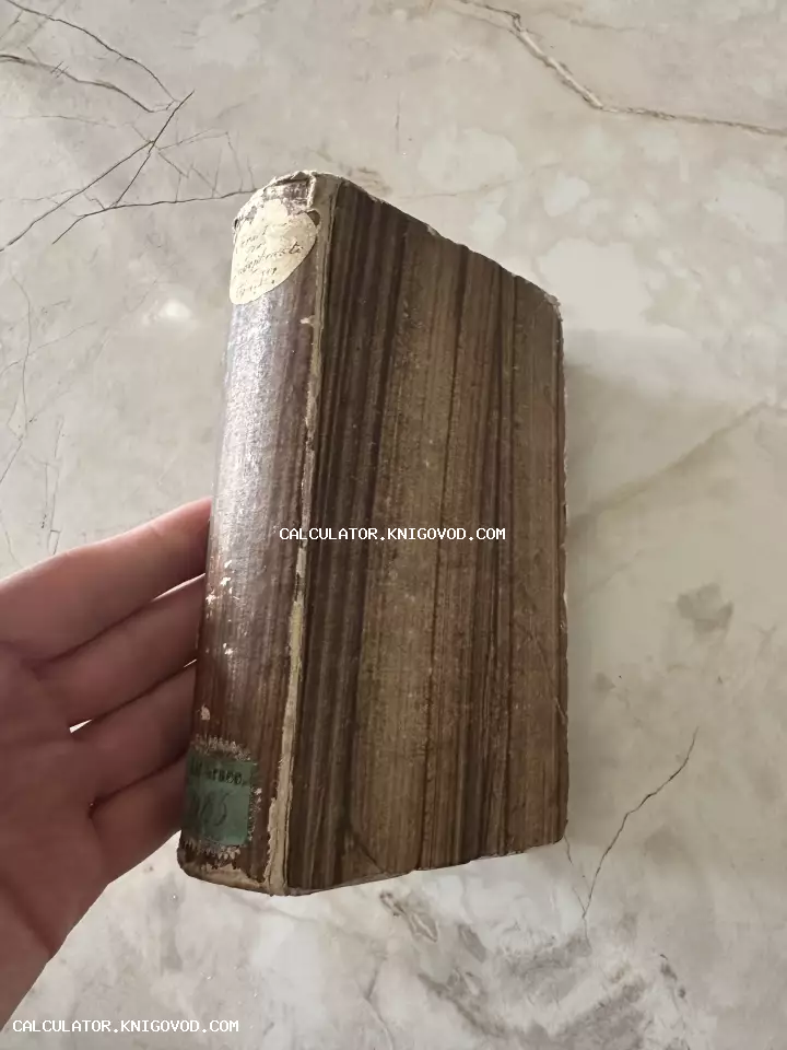 Старинная книга с коричневым потертым корешком и бумажными наклейками, удерживаемая рукой на фоне светлого мрамора.