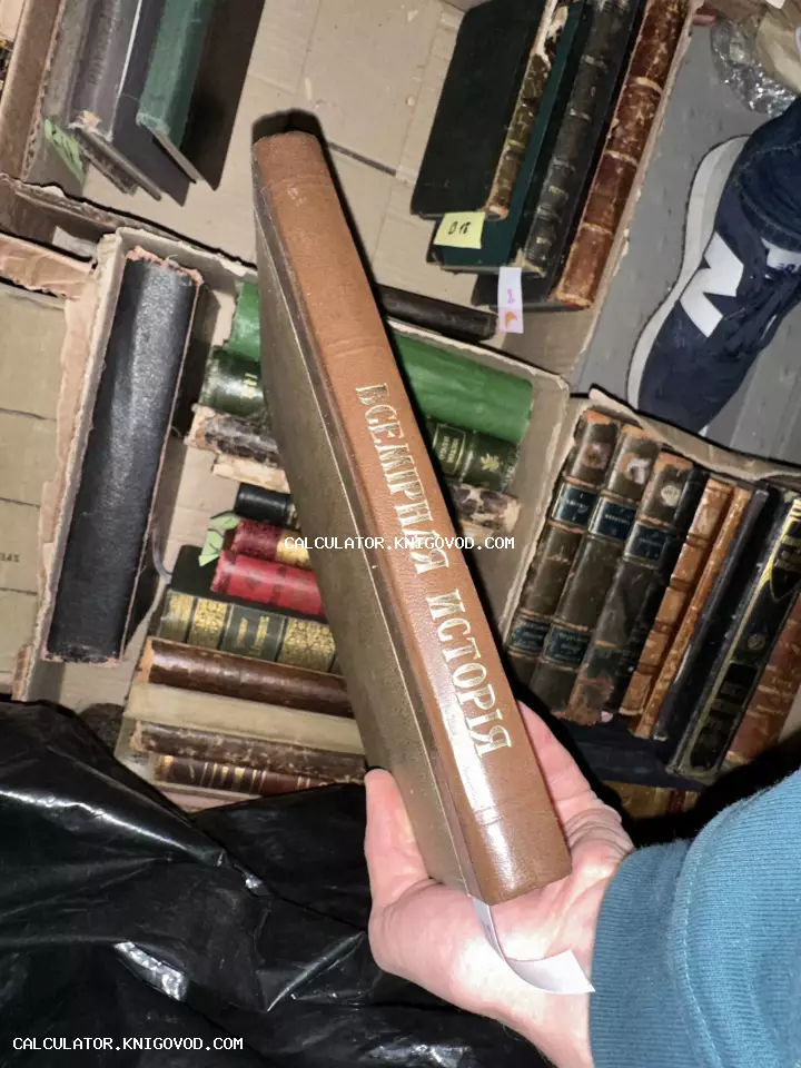 Старинная книга с золотым тиснением «Всемирная история» на корешке в руках человека на фоне коробок с другими книгами.